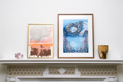 Two framed posters on a mantle